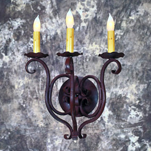 A beautifully crafted wrought iron sconce featuring intricate scrollwork and three candle-like lights with amber bulbs, set against a textured backdrop.